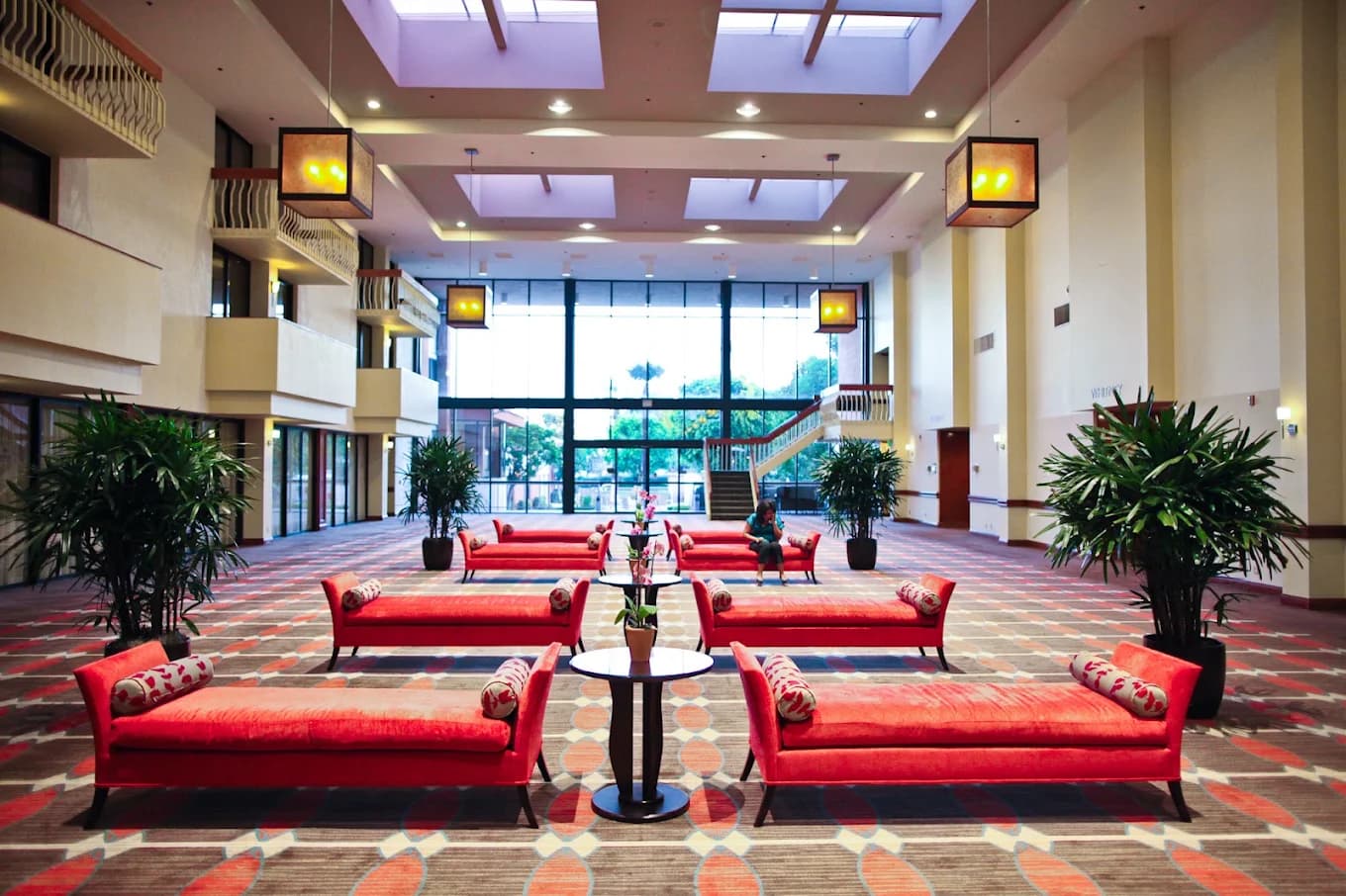 Ontario Airport Hotel & Conference Center atrium lobby with red chaise lounges, patterned carpet and tall glass windows