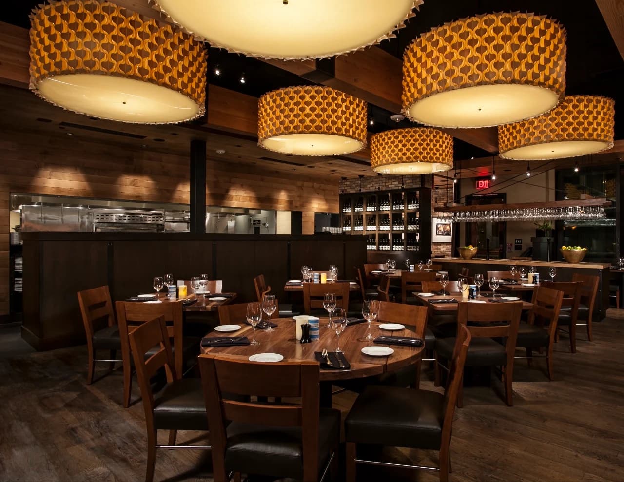 Dining room at Paul Martin's American Grill with drum pendant lights, wood tables and an open kitchen
