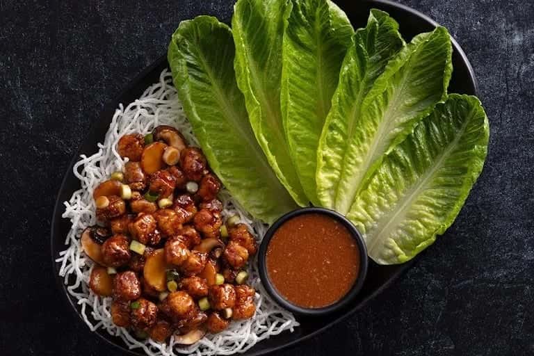 Chicken lettuce wraps: minced chicken and mushrooms over crisp noodles with romaine leaves and a dish of sauce
