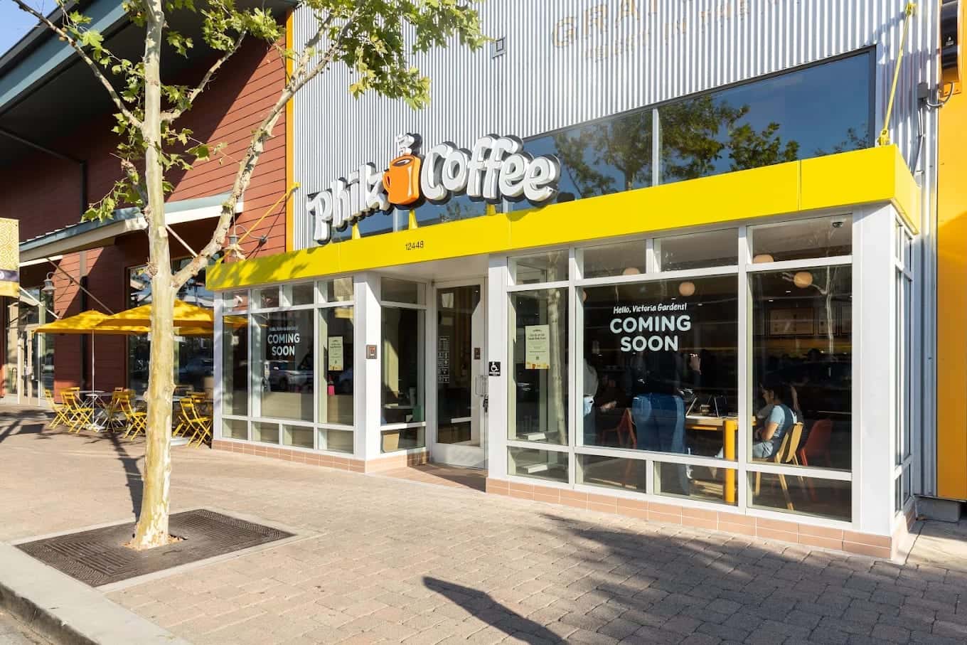 The Philz Coffee storefront under a yellow awning, a coming-soon notice in the window and pavement tables alongside