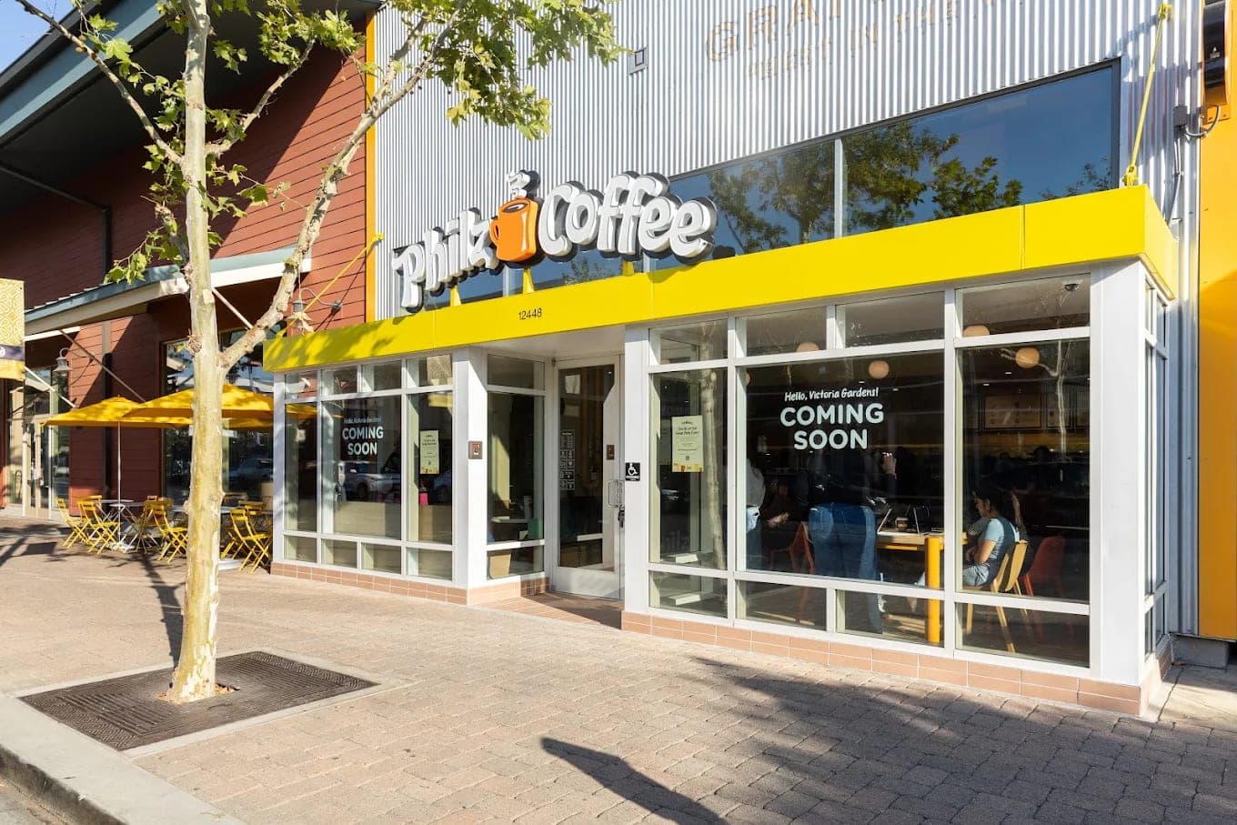 The Philz Coffee storefront under a yellow awning, a coming-soon notice in the window and pavement tables alongside