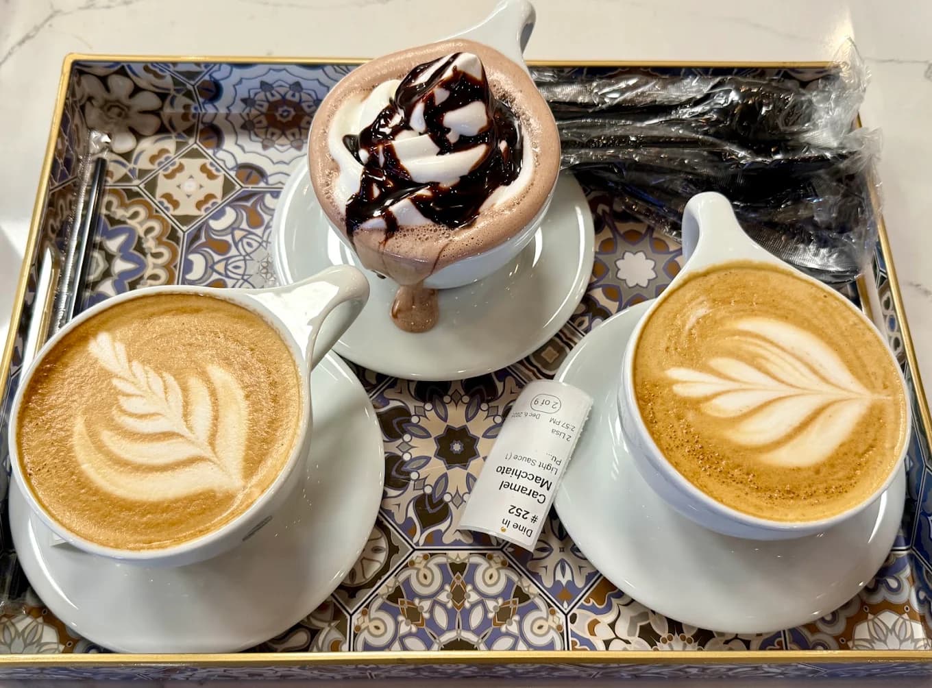 Tray with two latte-art coffees and a whipped-cream mocha at Qamaria Yemeni Coffee Co