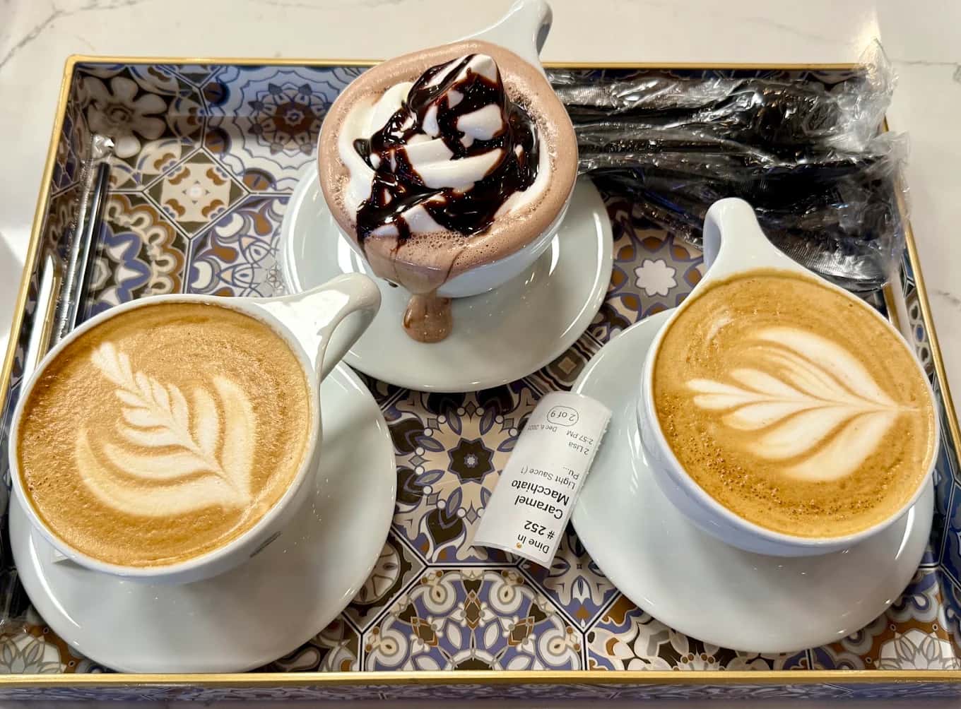 Tray with two latte-art coffees and a whipped-cream mocha at Qamaria Yemeni Coffee Co