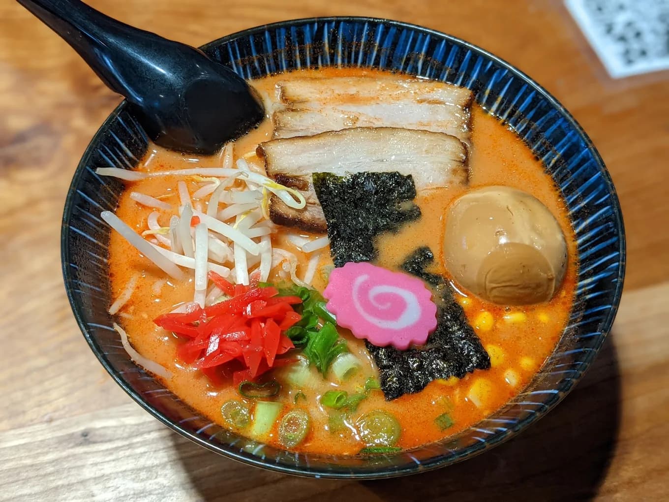Bowl of spicy ramen with chashu pork, soft egg, nori, corn and bean sprouts at Ramen Masuta