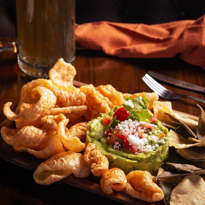 Chicharrones and tortilla chips with guacamole topped with pico and cheese at RAW Kitchen & Cantina