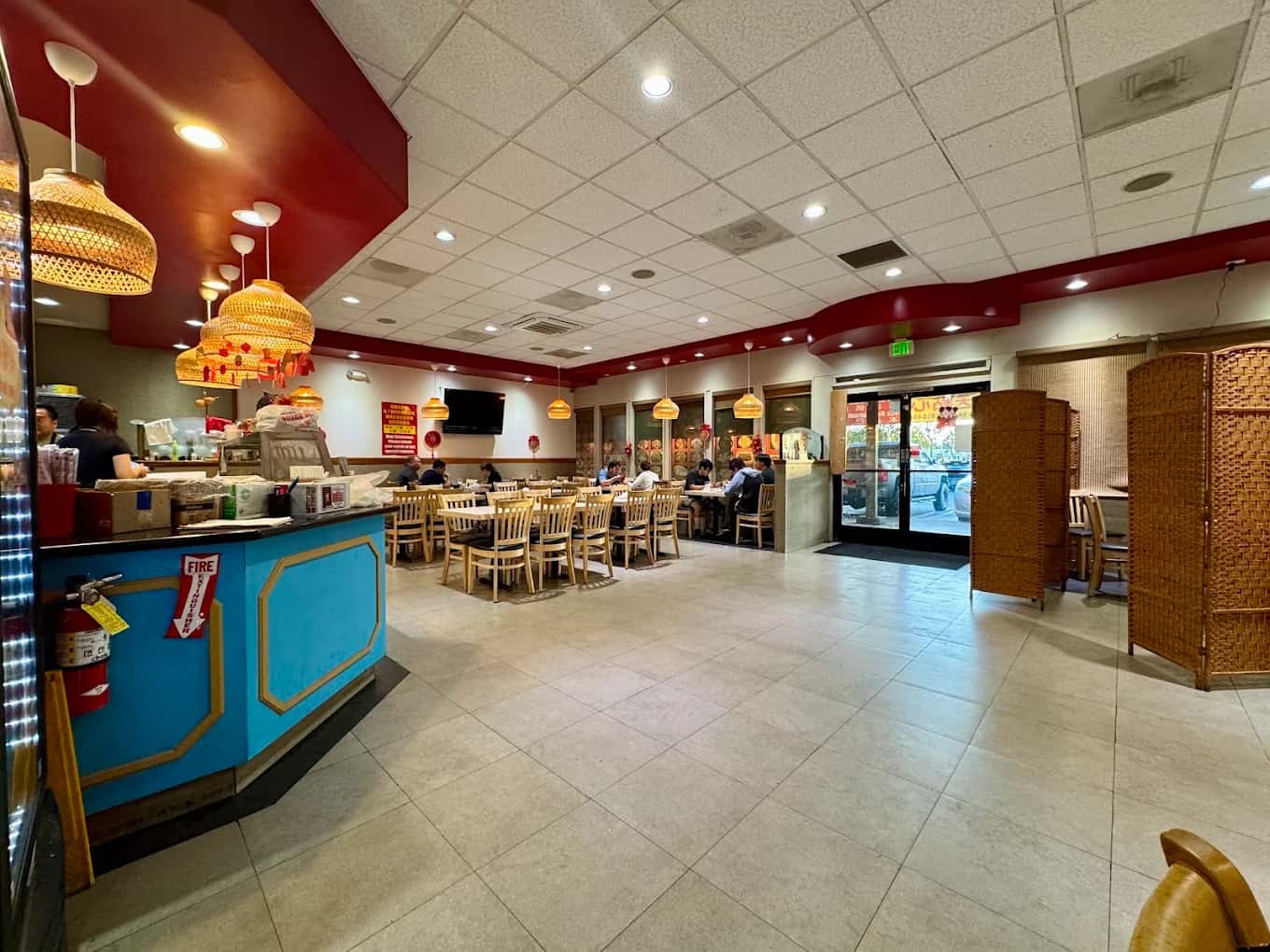 Dining room at Red Chili House with a blue front counter, wicker pendant lamps and wood chairs