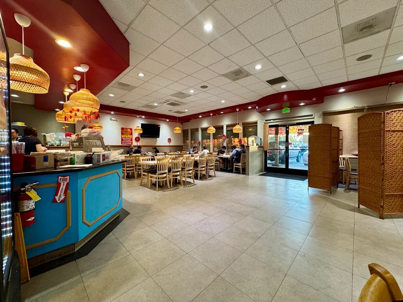 Dining room at Red Chili House with a blue front counter, wicker pendant lamps and wood chairs
