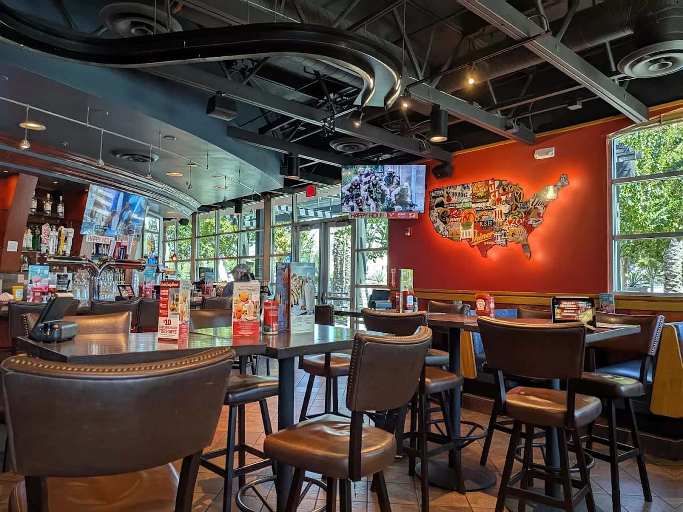 The dining room at Red Robin, high tables and leather stools beneath a map of the United States on a red wall