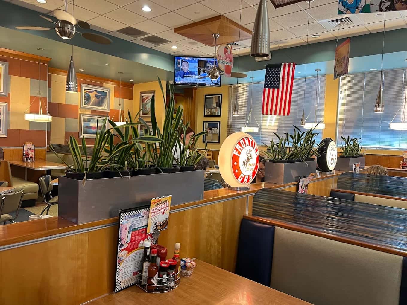 The dining room at Richie's, vinyl booths and planters under ceiling fans with an American flag on the far wall