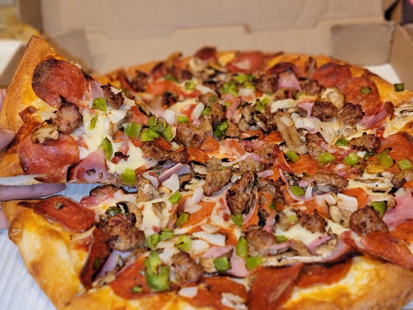 Slice lifted from a combination pizza with pepperoni, sausage, ham, mushrooms and green peppers at Sal's Pizza