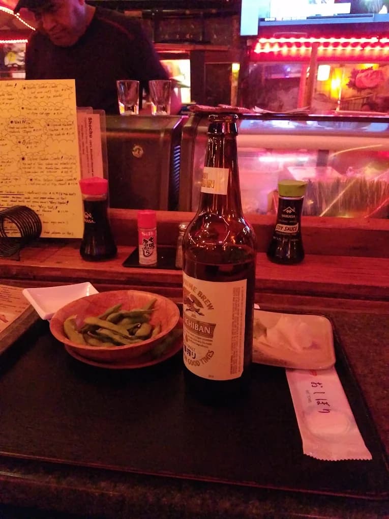 Bowl of edamame and a bottle of Kirin Ichiban on a tray at the sushi bar at Satsuma Sushi Japanese Restaurant