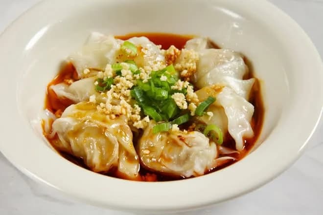 Wontons in red chili oil topped with crushed peanuts and green onion at Seven Grams