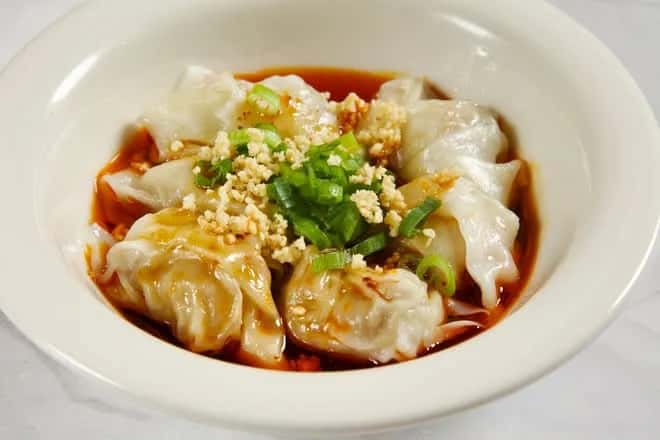 Wontons in red chili oil topped with crushed peanuts and green onion at Seven Grams