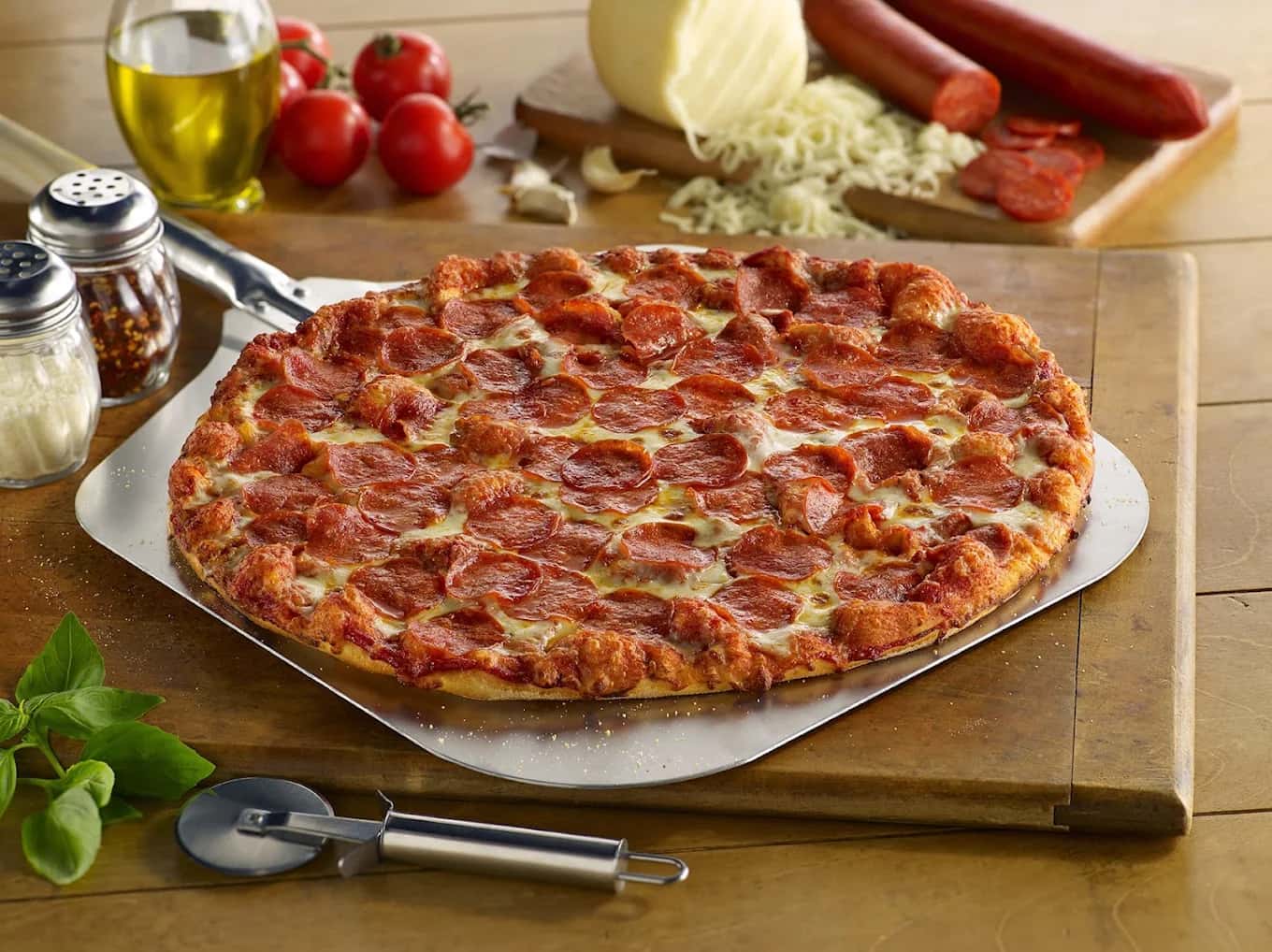 Pepperoni pizza on a metal peel with a pizza cutter, tomatoes and cheese at Shakey's Pizza Parlor