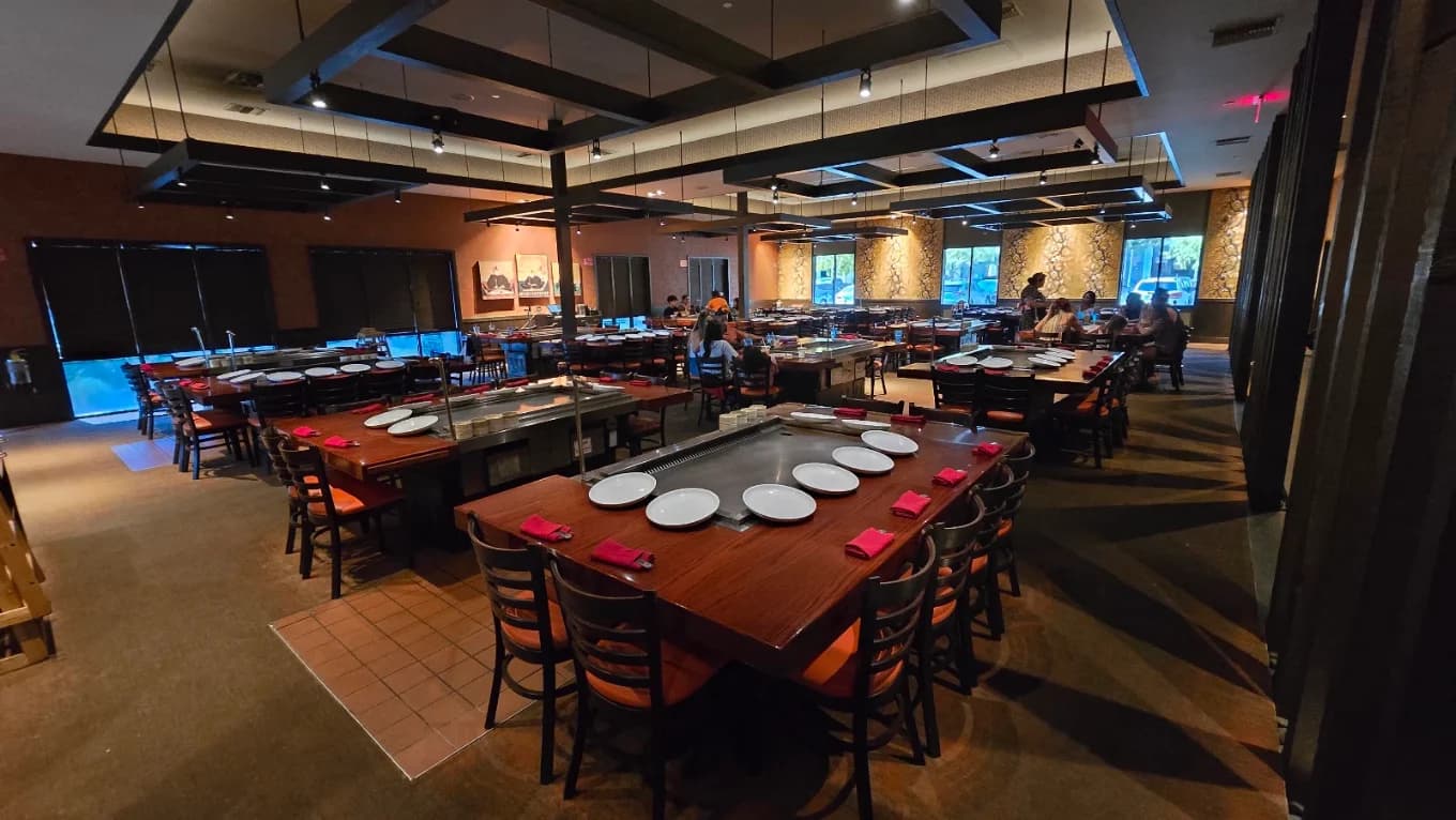 Dining room with teppanyaki grill tables set with white plates and red napkins at Shogun Restaurant