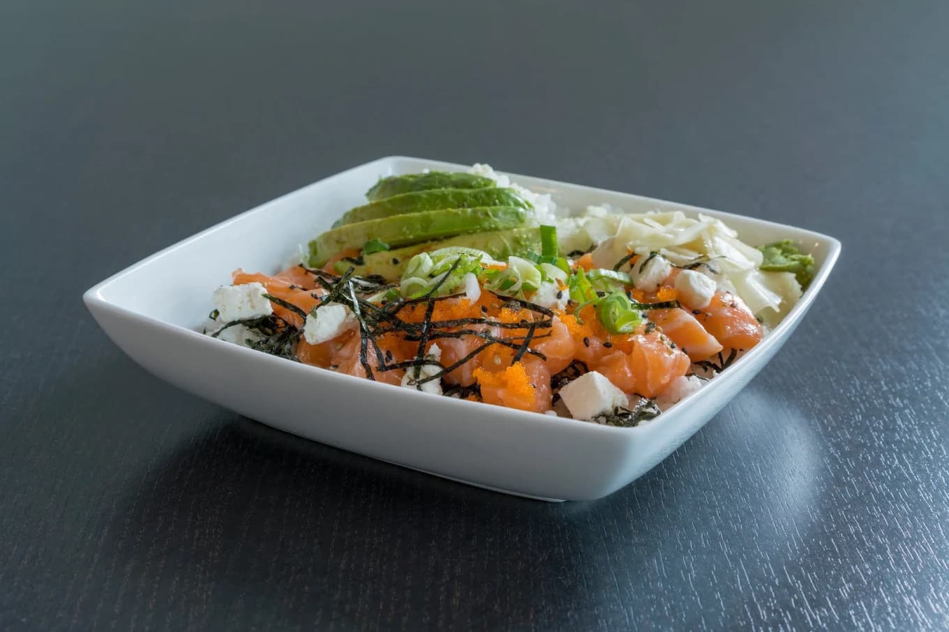 Salmon poke bowl with avocado, seaweed, green onion and masago in a square white dish at Skipjack Poke Co