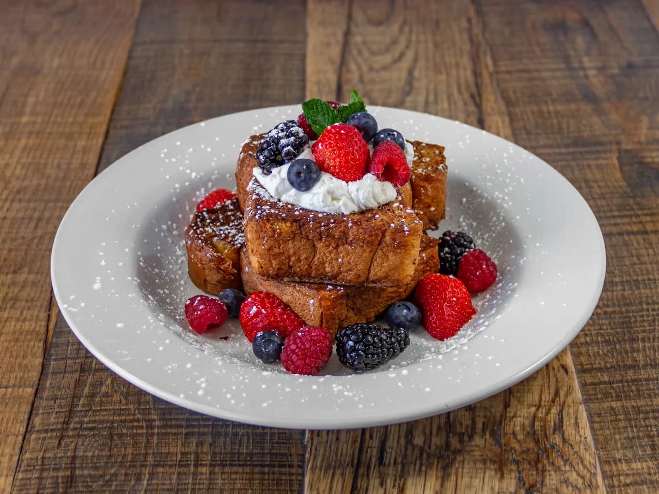 Stacked French toast with whipped cream, mixed berries and powdered sugar at Sunny's Cafe