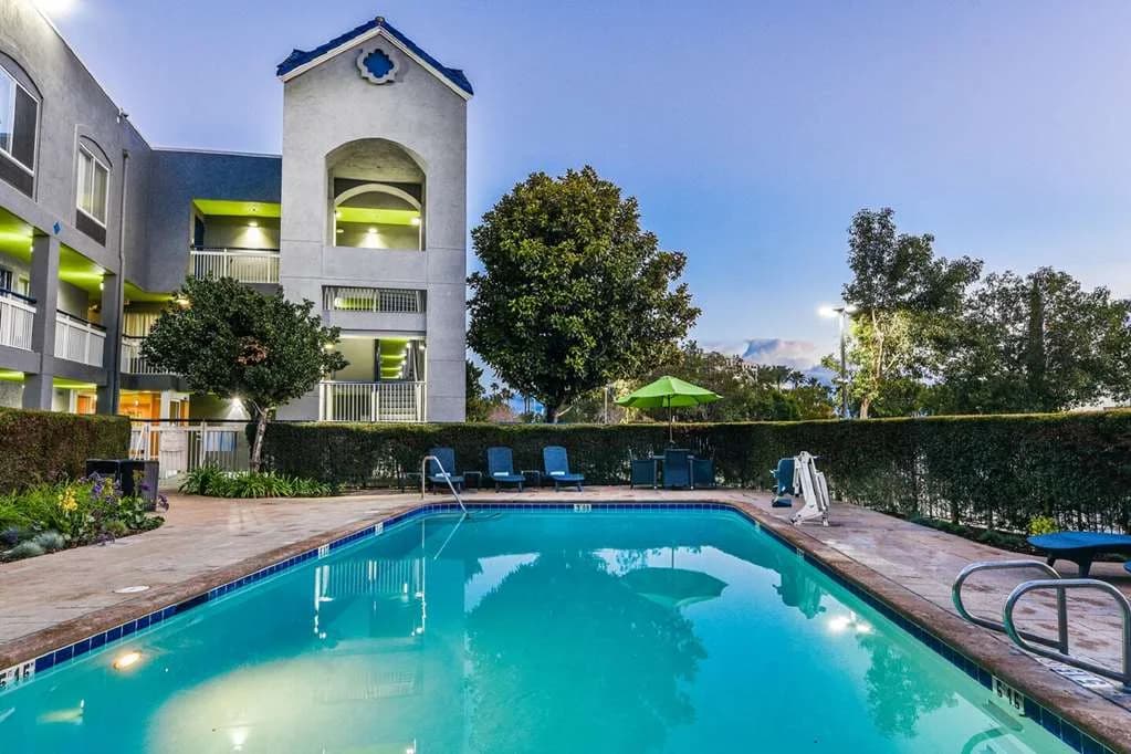 Outdoor pool at dusk at SureStay by Best Western Ontario Airport, with lounge chairs and the hotel tower behind