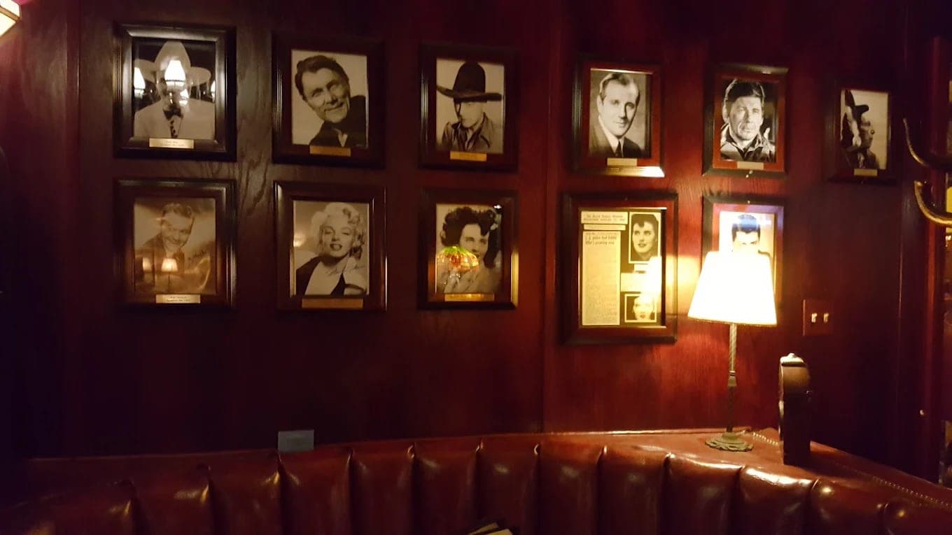 A wall of framed black-and-white celebrity portraits above a leather banquette in The Sycamore Inn's dining room