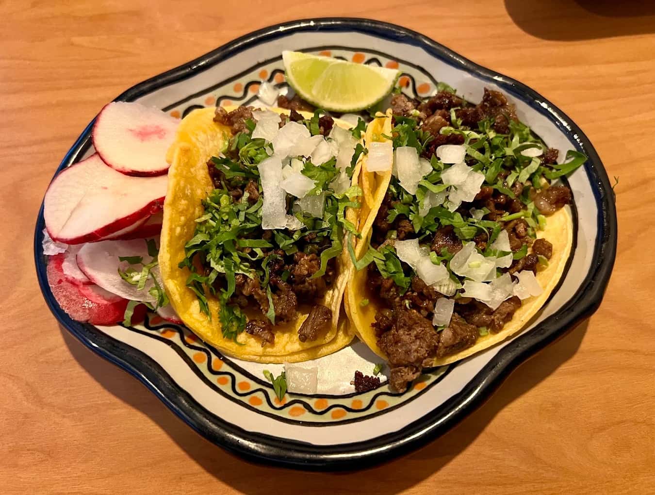 Two carne asada street tacos with onion, cilantro, radish and lime at T & T Authentic Mexican Restaurant