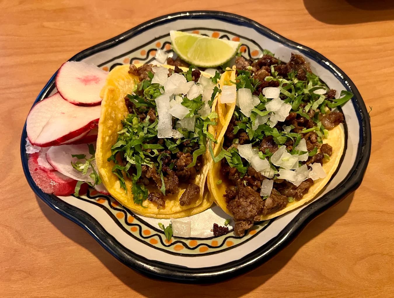 Two carne asada street tacos with onion, cilantro, radish and lime at T & T Authentic Mexican Restaurant
