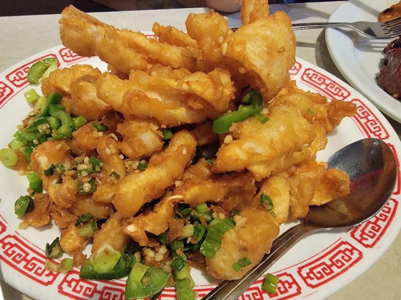 Battered fried fish fillets with jalapeño and green onion on a red-trimmed plate at Tai Pan House