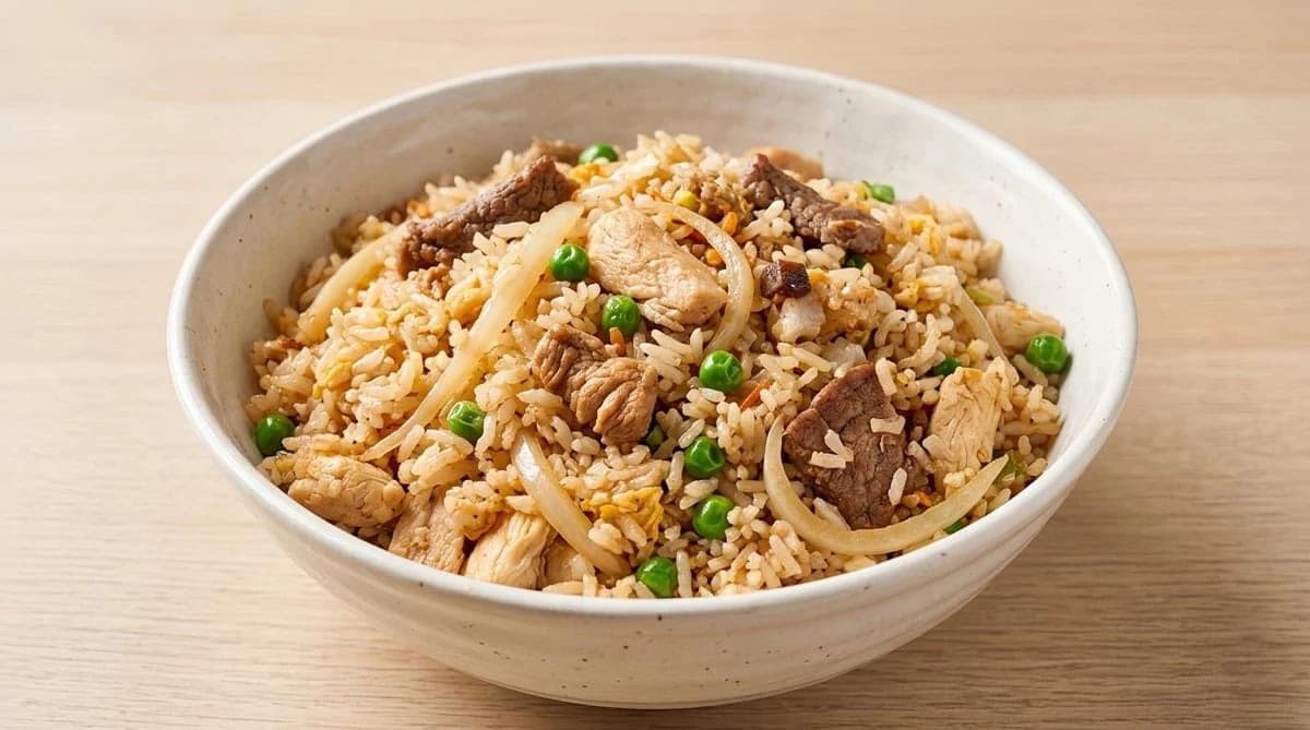 Bowl of fried rice with sliced beef, chicken, onion, peas and egg from Thai T