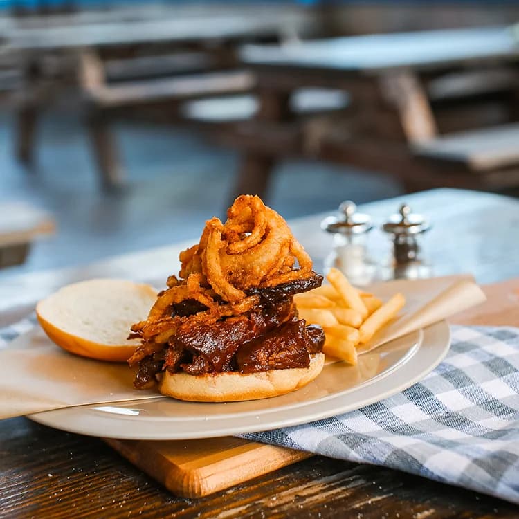Open-faced barbecue sandwich topped with crispy onion strings, with fries, at The Hitch Burger Grill