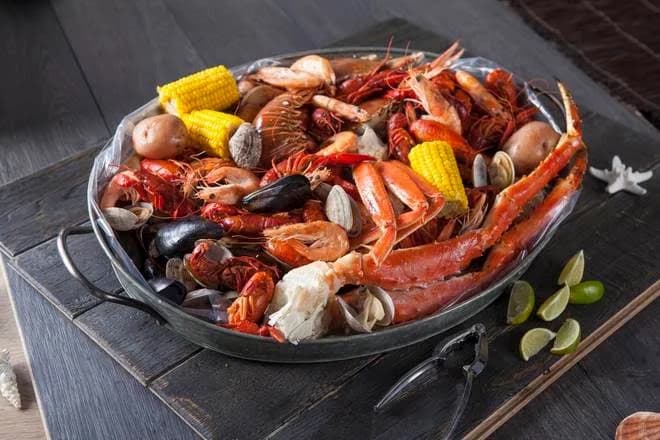 Seafood boil tray with crab legs, crawfish, shrimp, clams, corn and potatoes from The Mad Claw