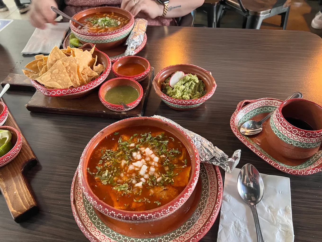 Bowls of red pozole with cilantro and onion, chips, salsas and guacamole at The Pozole Place