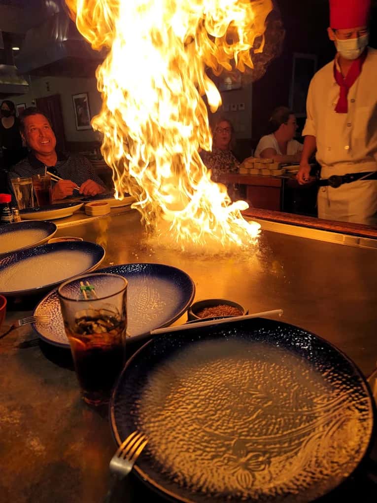 Chef sending a tall flame up from the teppanyaki grill at Wabi Sabi as diners watch
