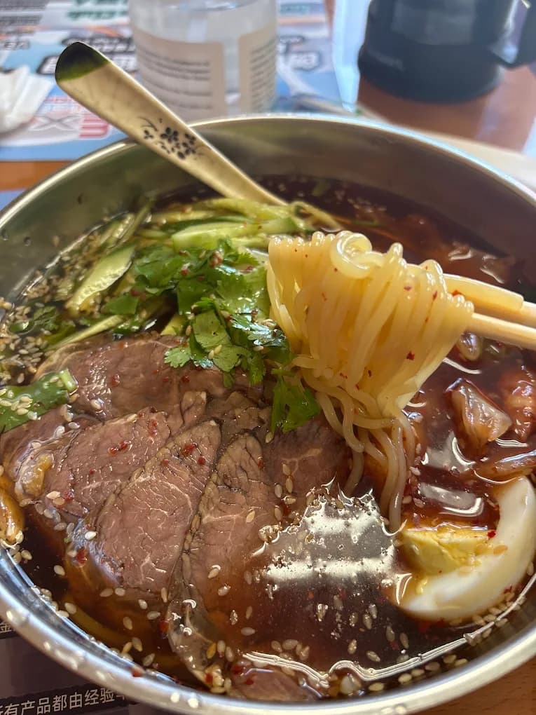 Bowl of cold noodle soup with sliced beef, cucumber, cilantro and egg at YueLai Restaurant 悦来餐厅