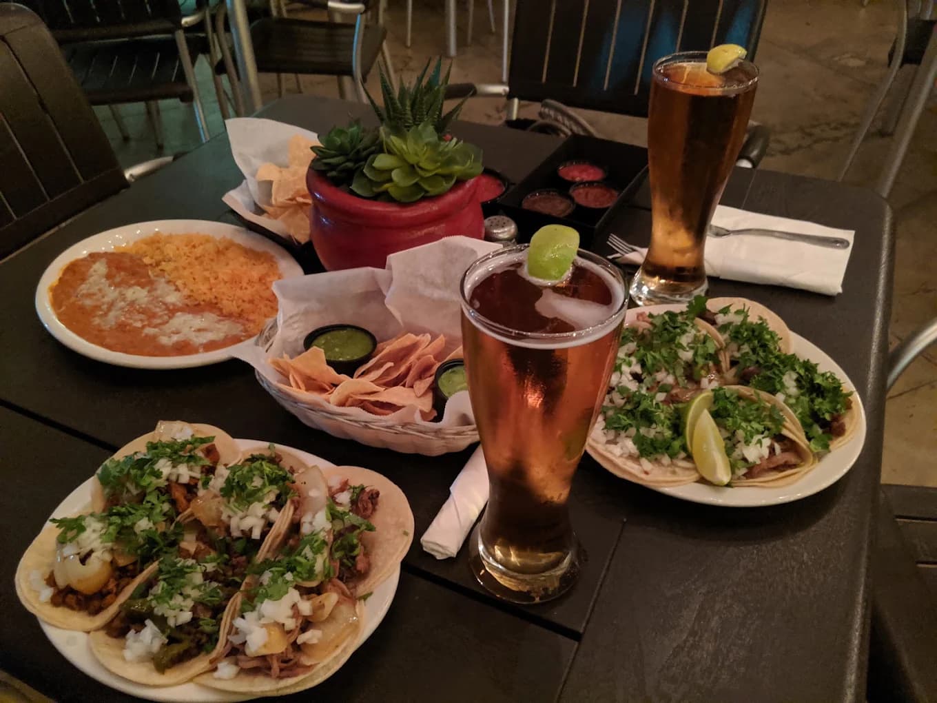 Street tacos, rice and beans, chips with salsa and two beers on a table at Zendejas Mexican Restaurant & Bar